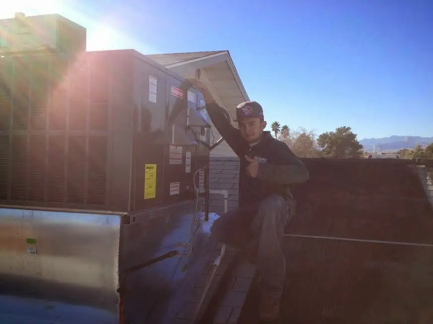 HVAC technician performing Air Duct Repair on a rooftop unit in Durango